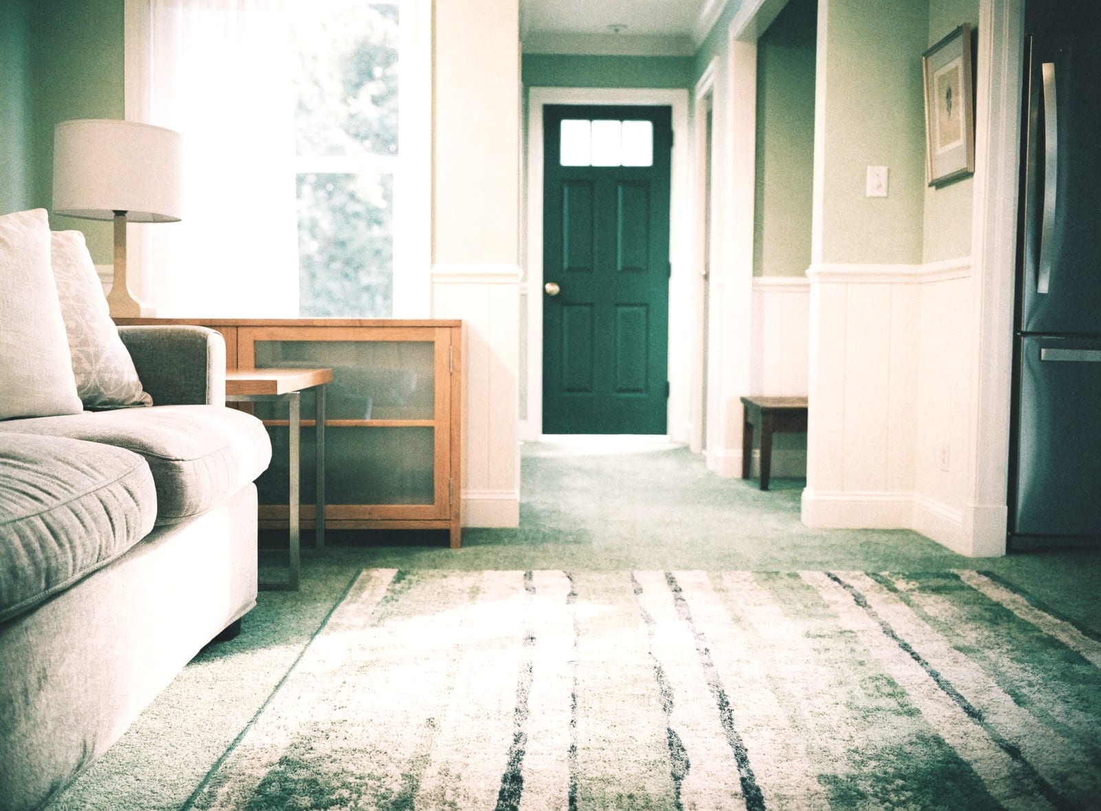 Living room with a grey sofa, a striped rug and a green front door